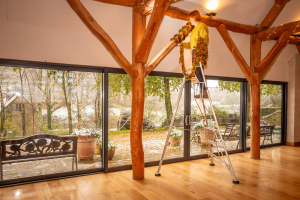 Person hanging tinsel from beams whilst stood on a ladder. 